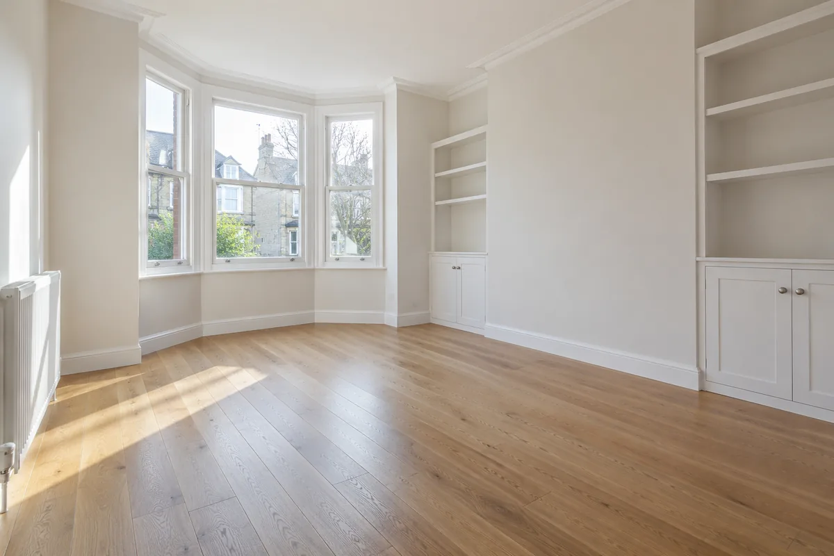 Empty rental room with timber flooring and a bay window